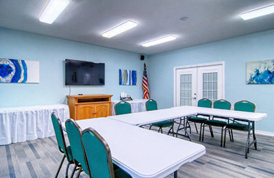 Meeting room at Alister Square Inn with rows of chairs, a TV, and bright modern decor