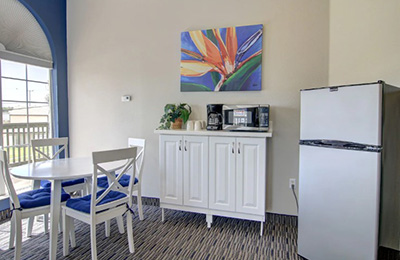 Dining area of Deluxe Suite at Alister Square Inn with fridge, microwave, and colorful wall art