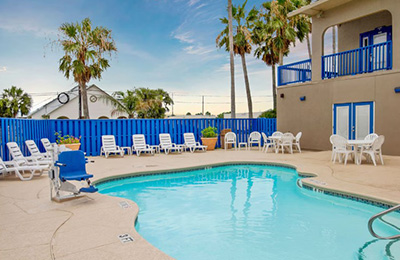Outdoor pool at Alister Square Inn with lounge chairs, palm trees, and a relaxing atmosphere