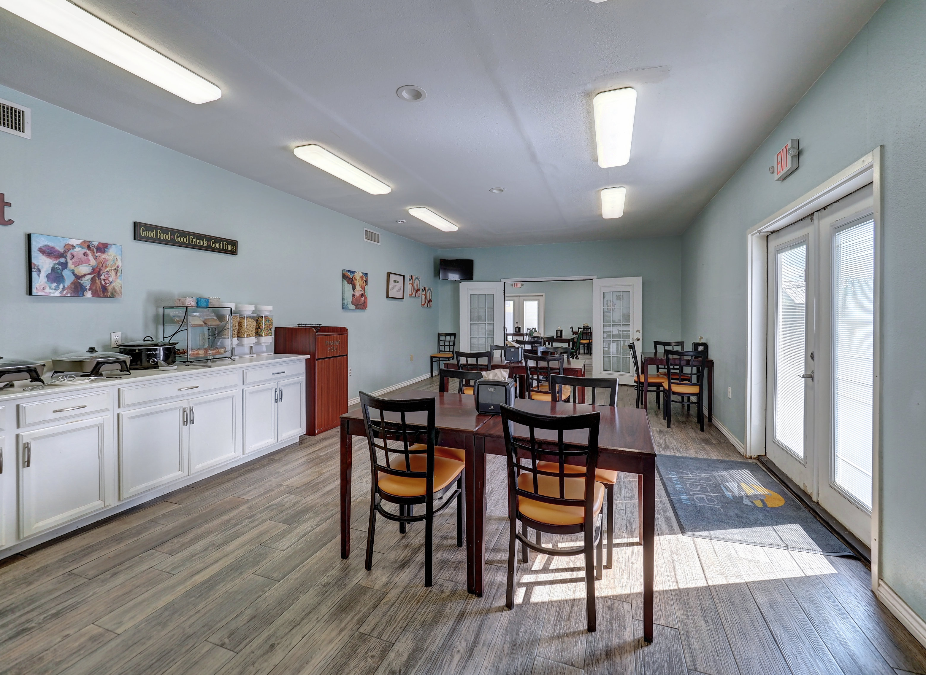 A dining area with tables and chairs, a counter with cabinets, and a coffee maker.