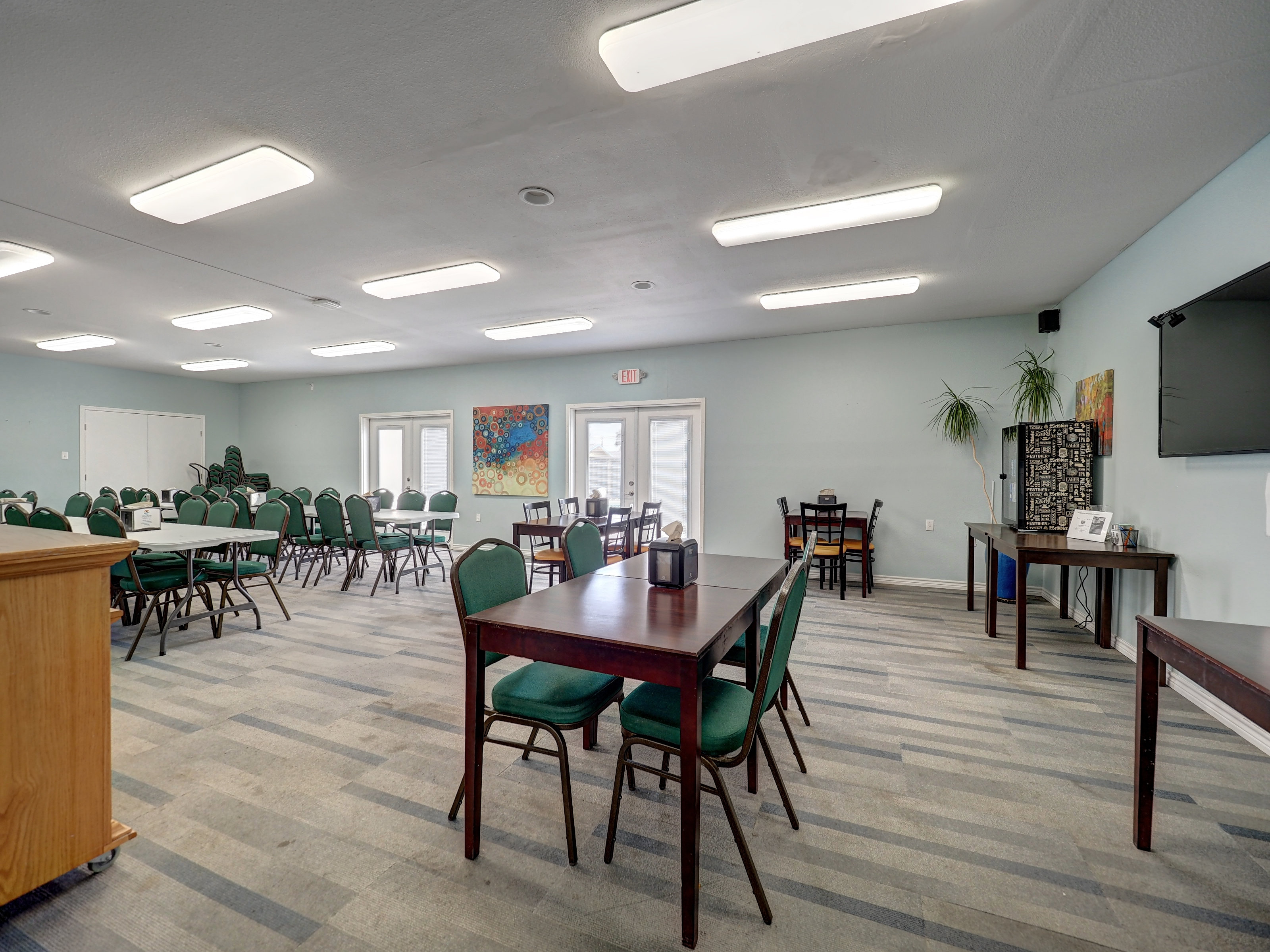 A large, empty meeting room with tables, chairs, and a podium.