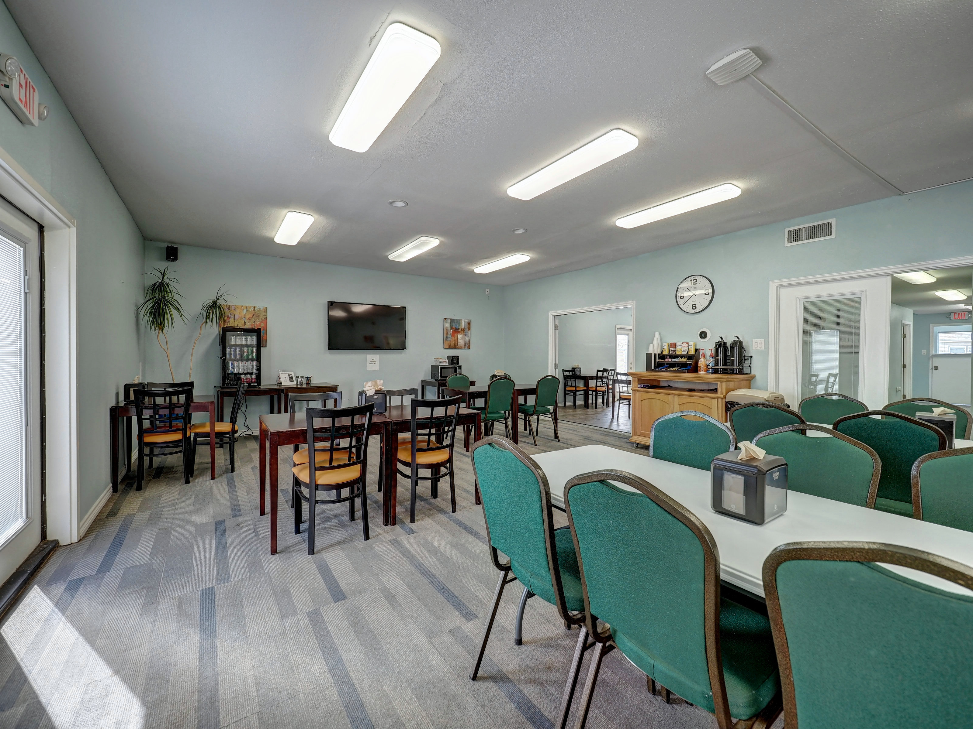 A dining area with tables and chairs, a TV on the wall, and a coffee station.