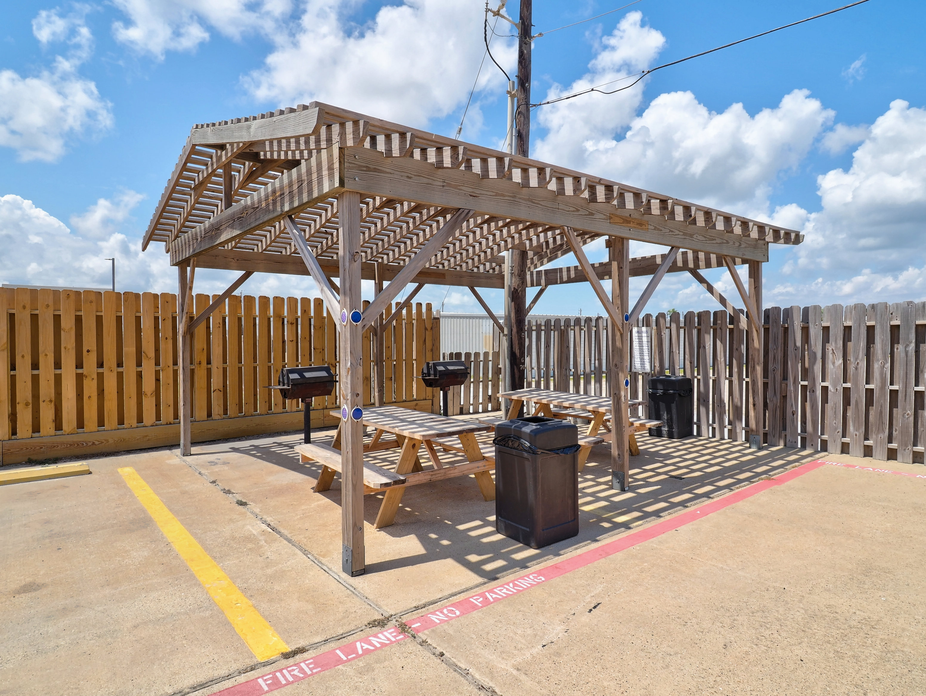 A picnic area with a pergola, grills, and picnic tables.