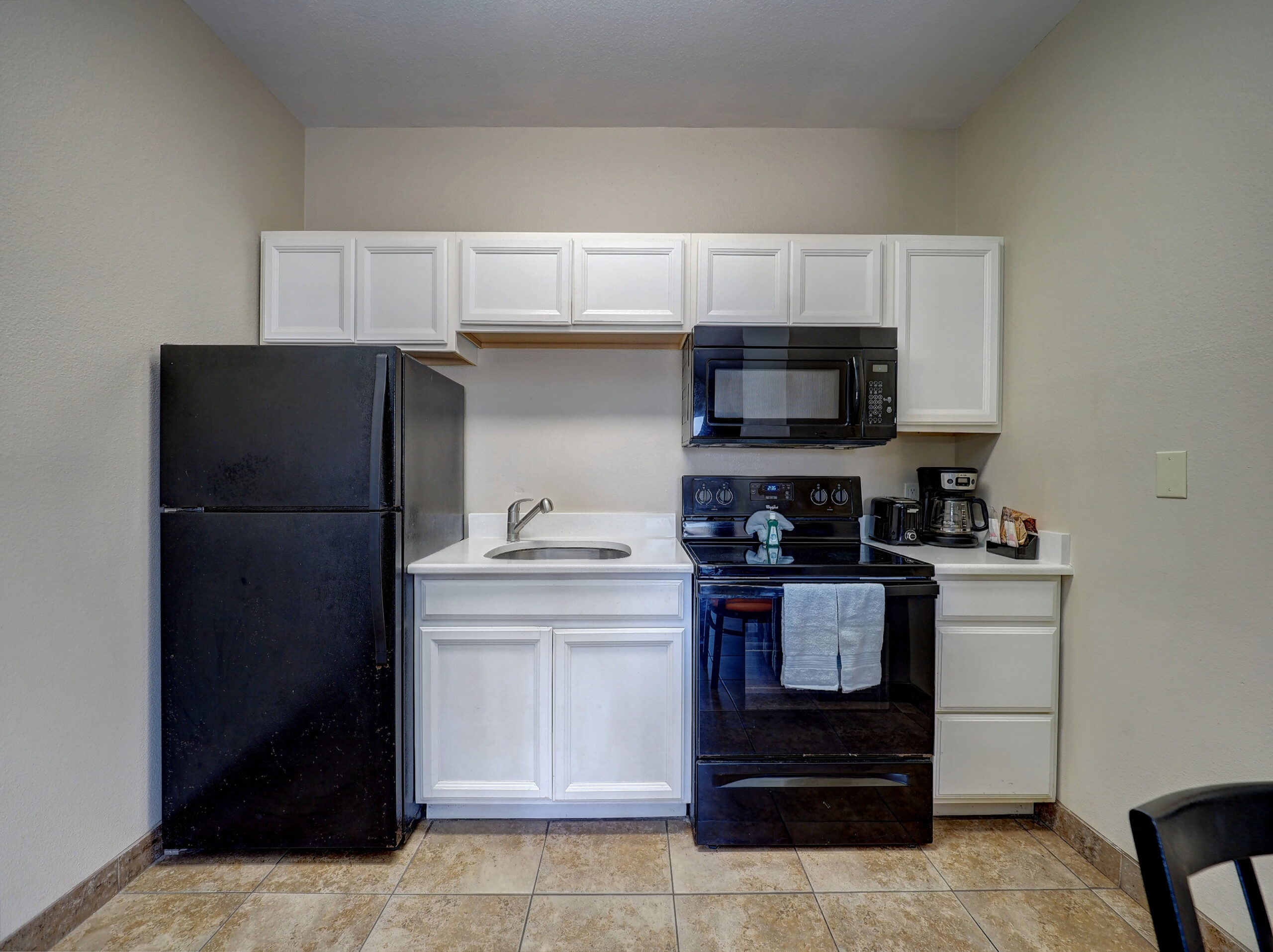 A compact kitchenette with black appliances and white cabinets.
