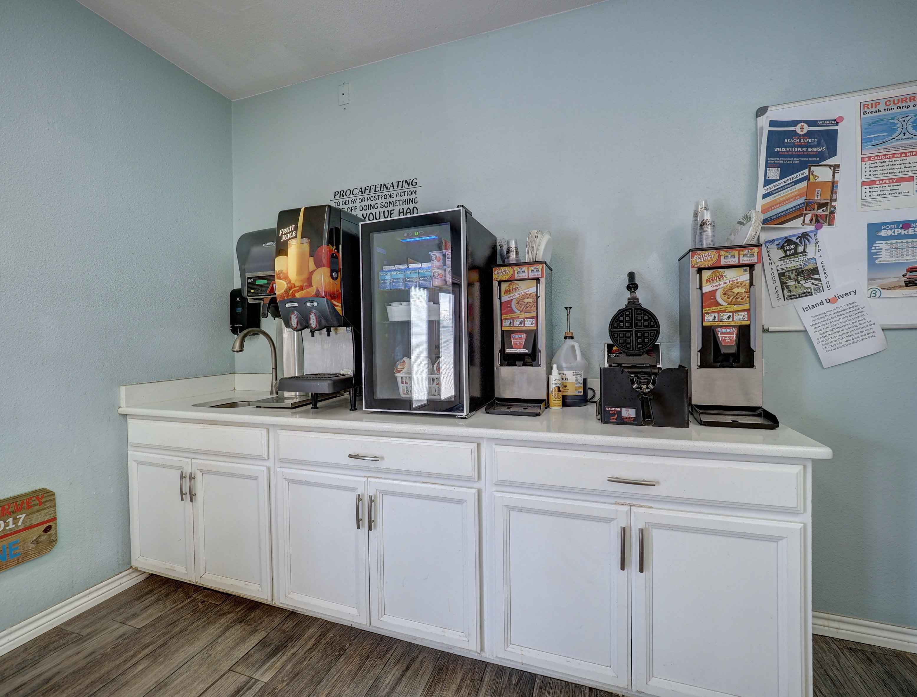 a counter with coffee machine, refrigerator, waffle maker and sink